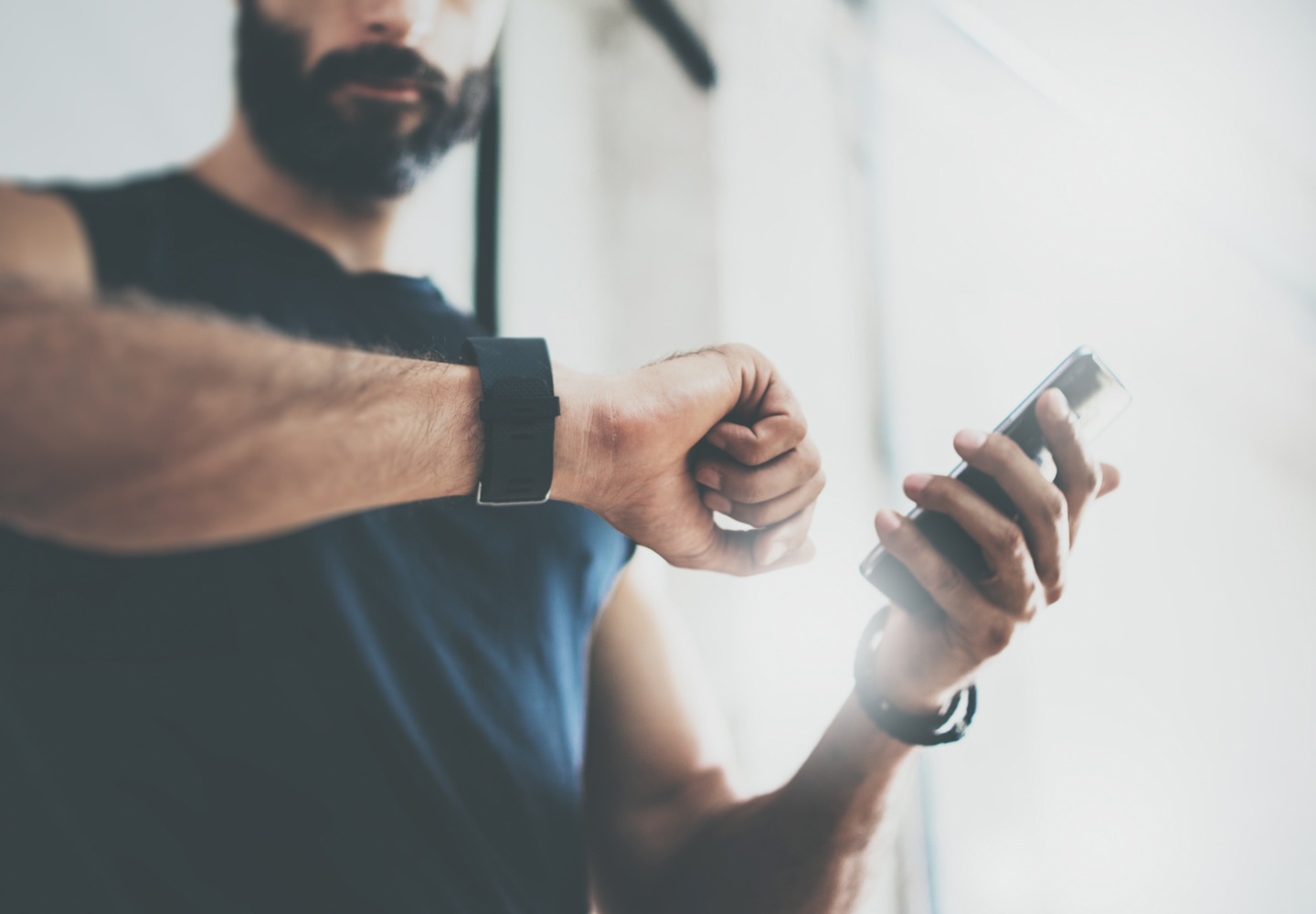 Sportlicher Mann nach Trainingseinheit prüft Fitnessergebnisse Smartphone